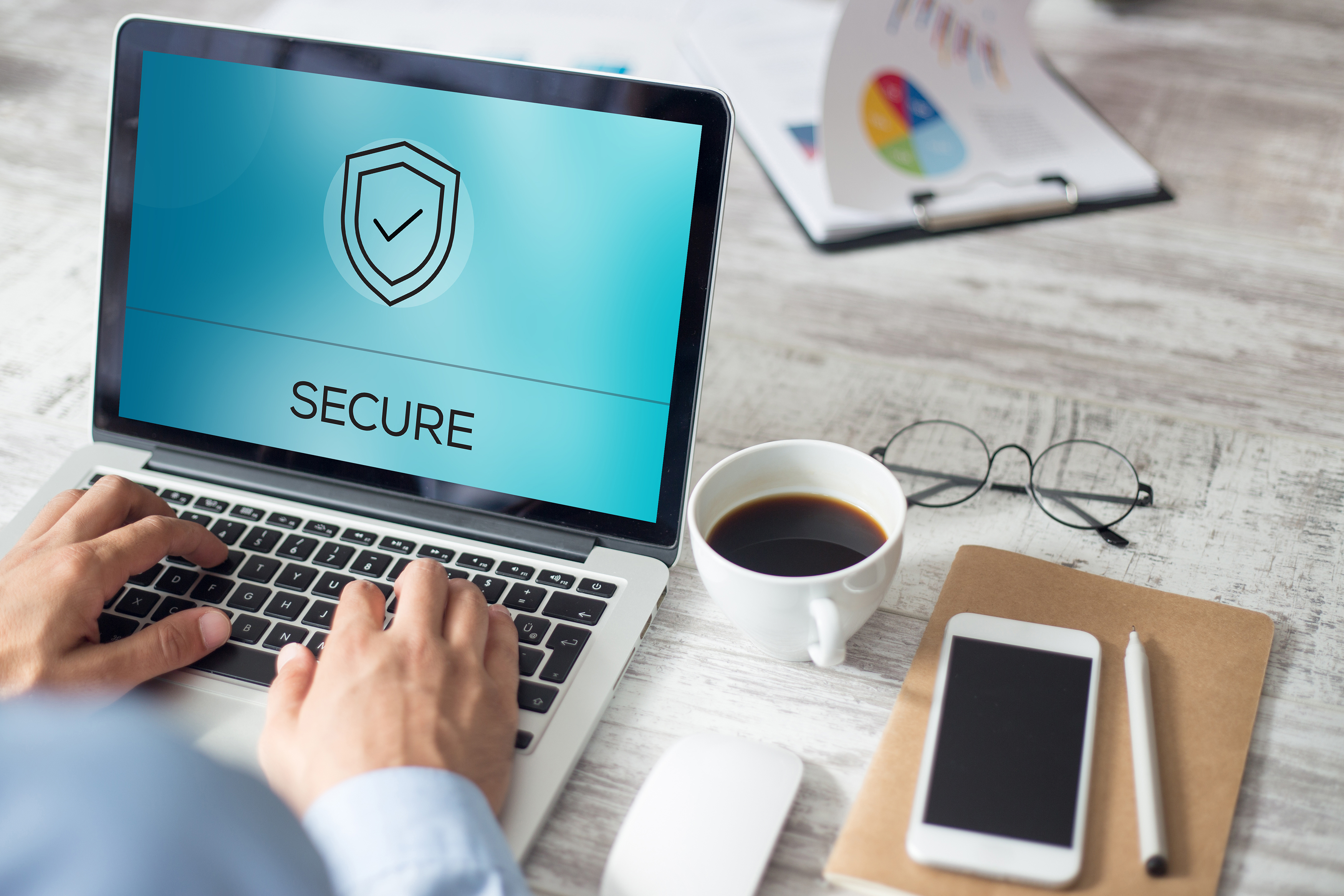 Close up of business person working on laptop which displays a cyber security screen.