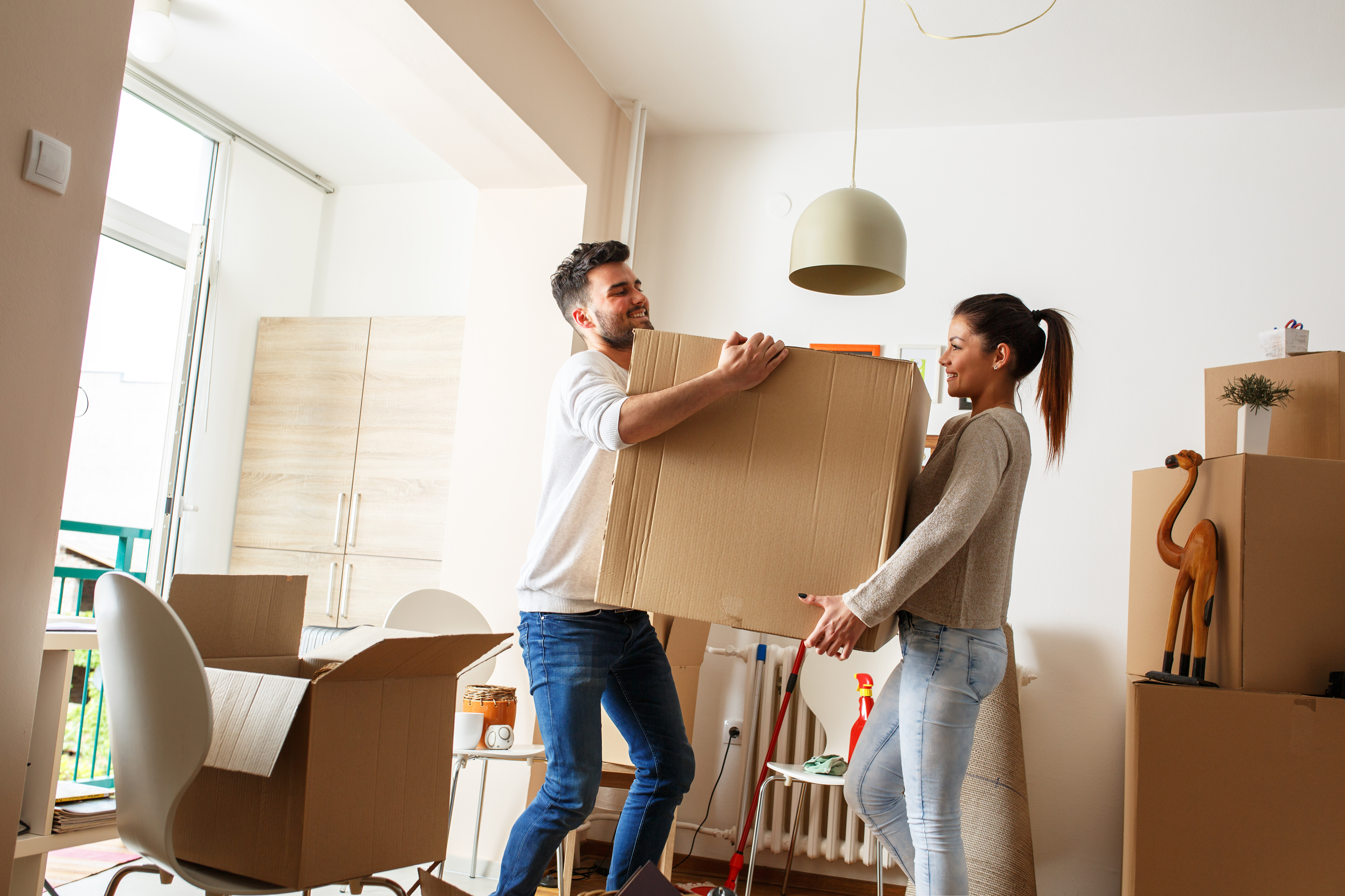 Two people moving boxes into a room.
