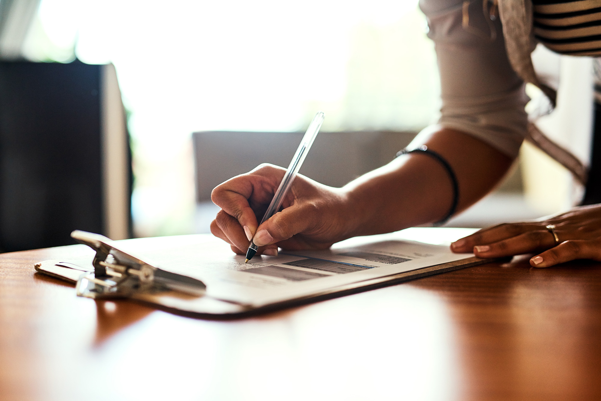 Close-up of a person writing on a checklist on a clipboard.