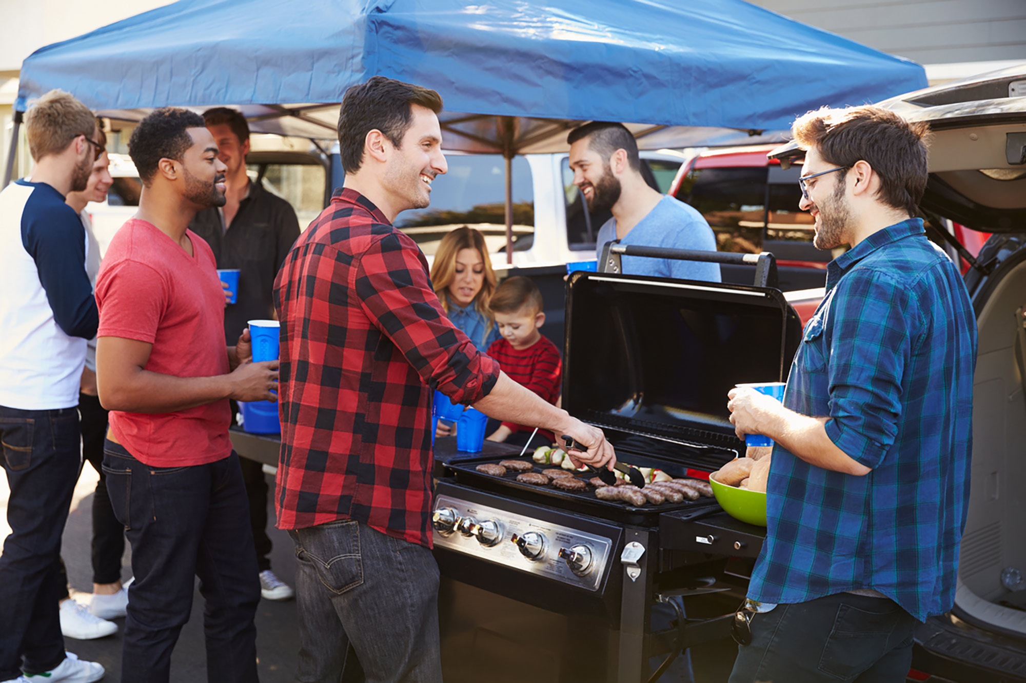A group of young men hanging out and grilling.