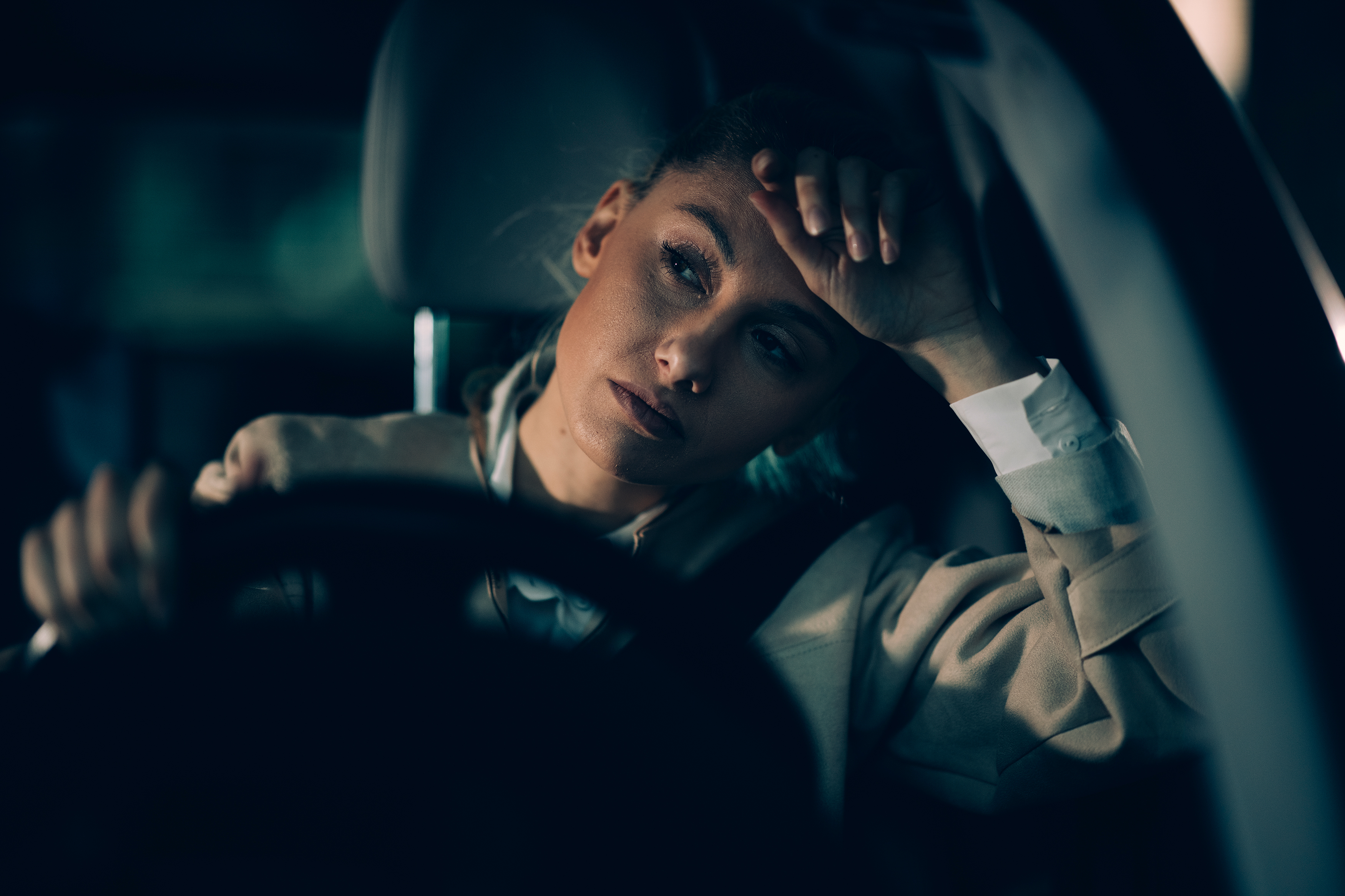 Close-up of tired looking woman behind the wheel of her vehicle.