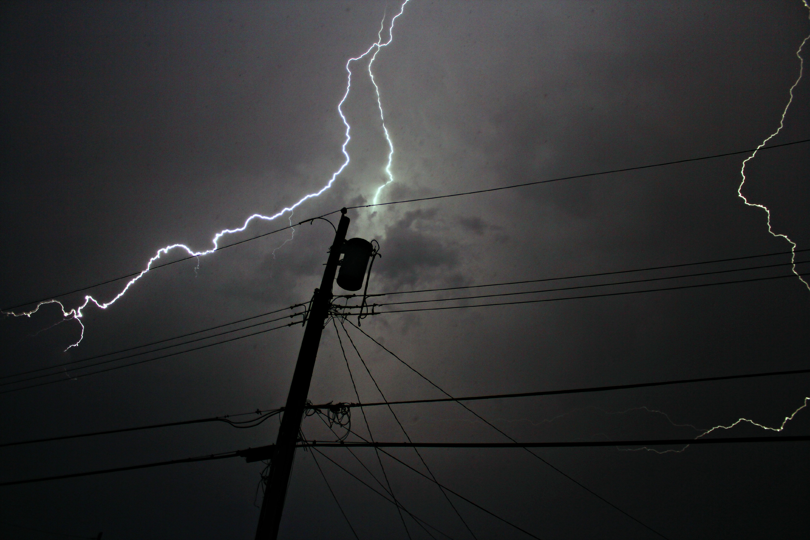 A dark sky with lightning striking a power line.