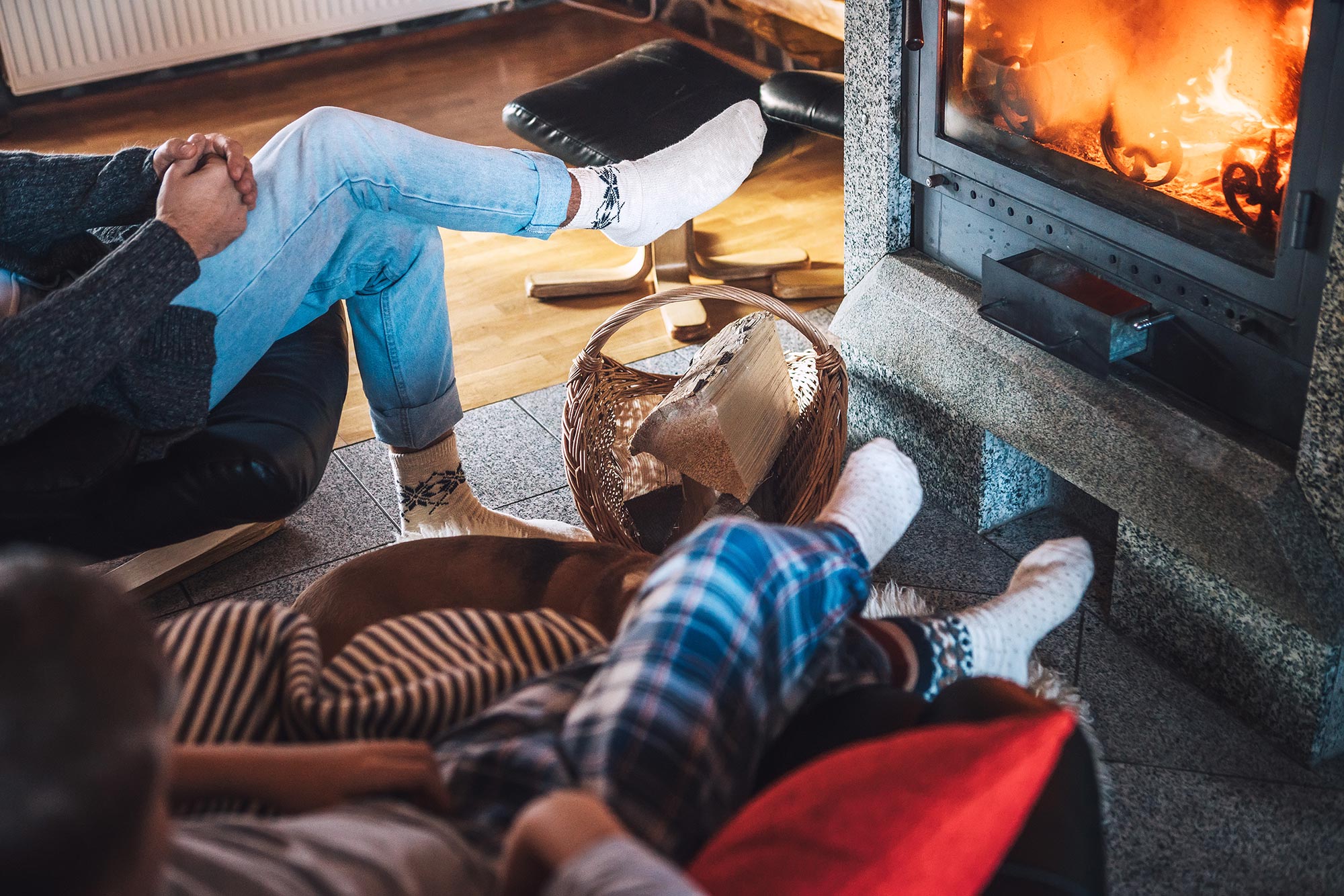 Two people relaxing in front of a cozy fire in their fireplace at home.