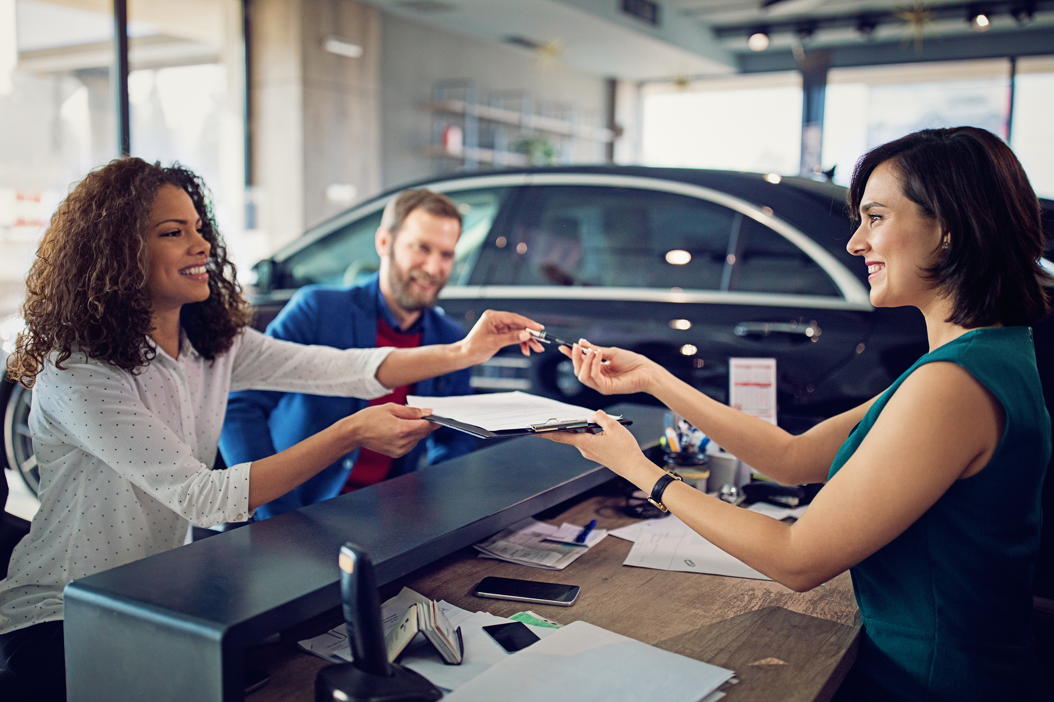 Couple signing contract for new vehicle at a dealership.