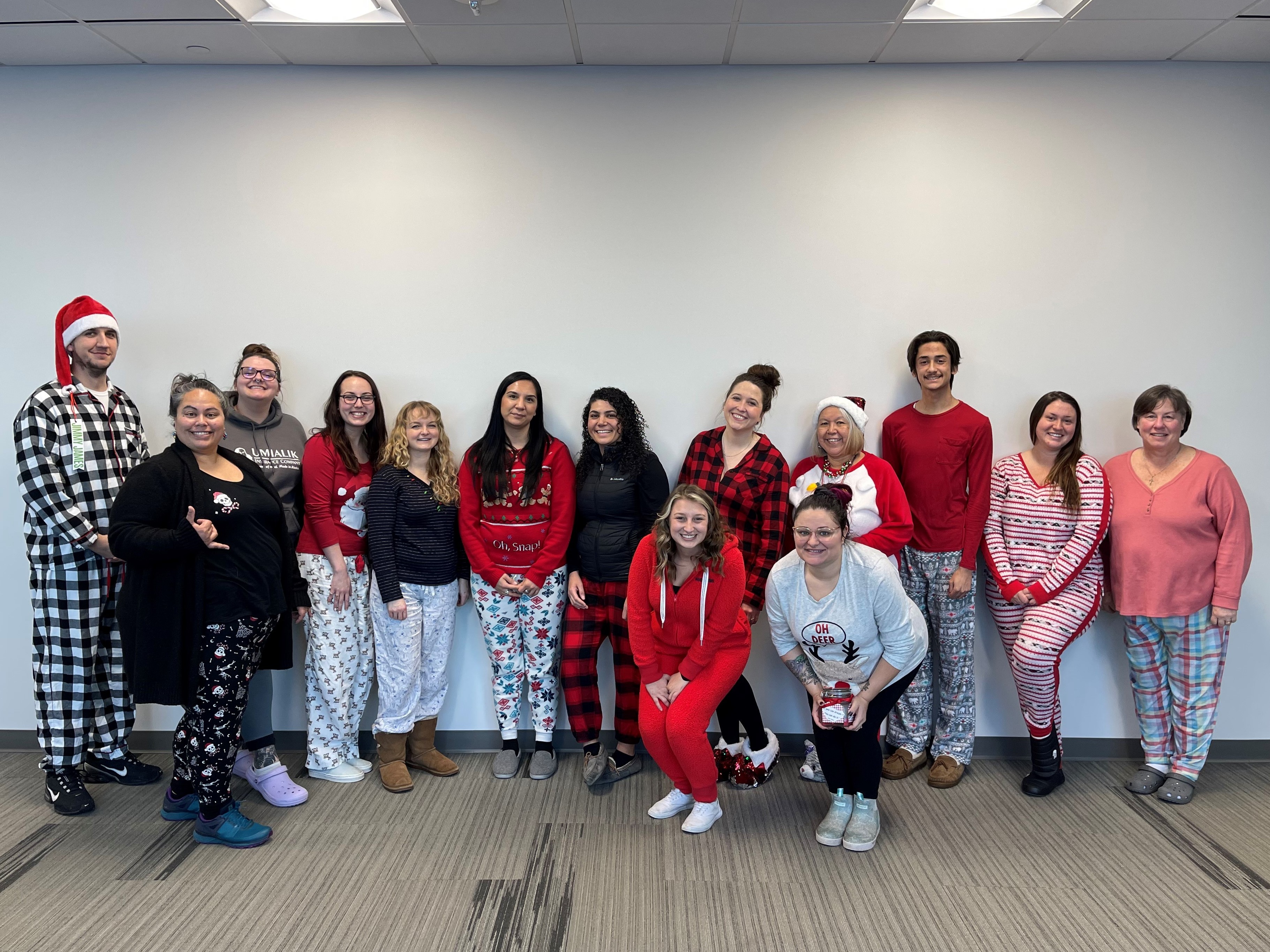 Group of Umialik employees posed together wearing festive holiday-themed pajamas.