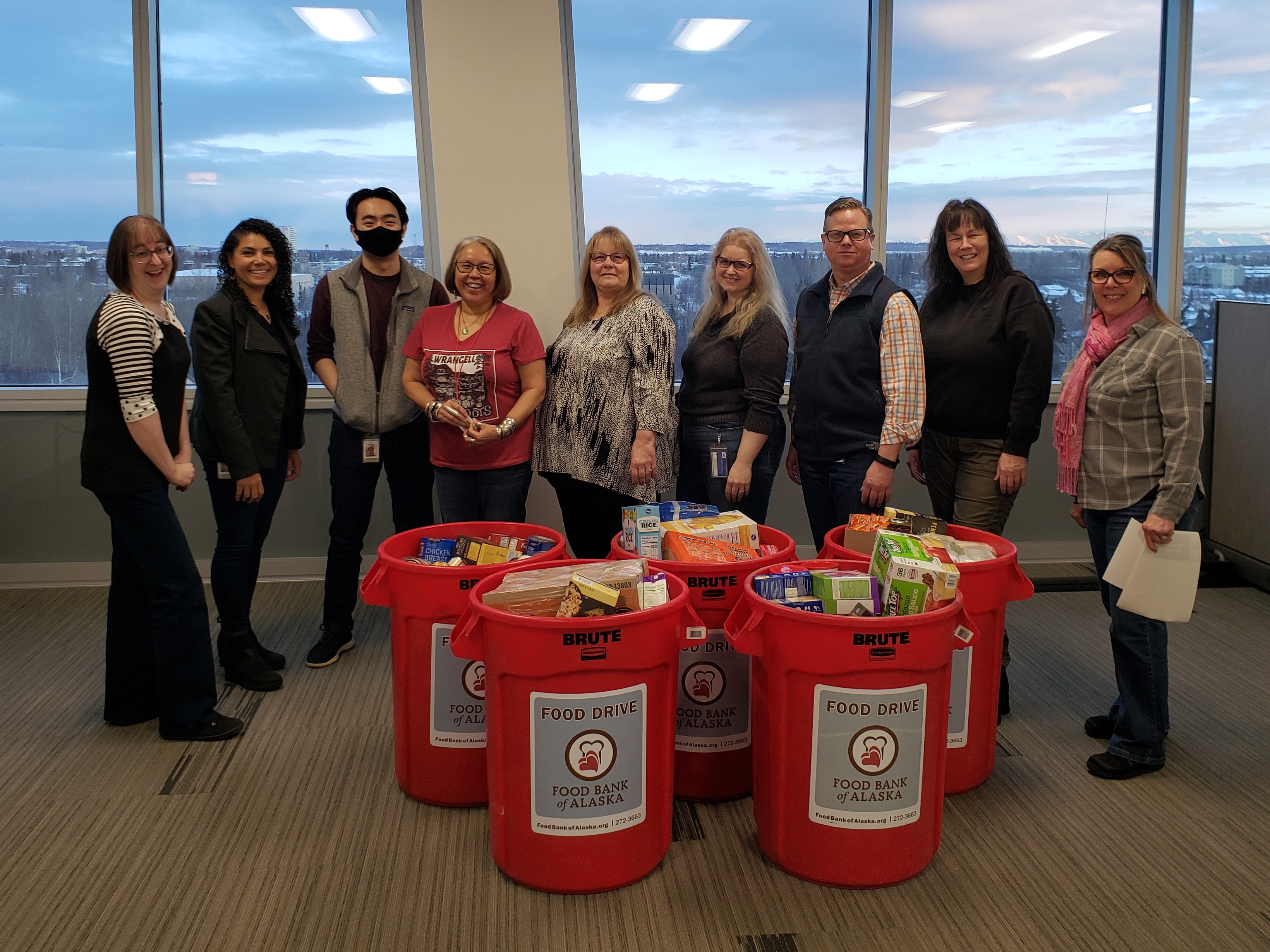 Group of Umialik employees gathered in front of five large bins full of food being donated to Food Bank of Alaska.