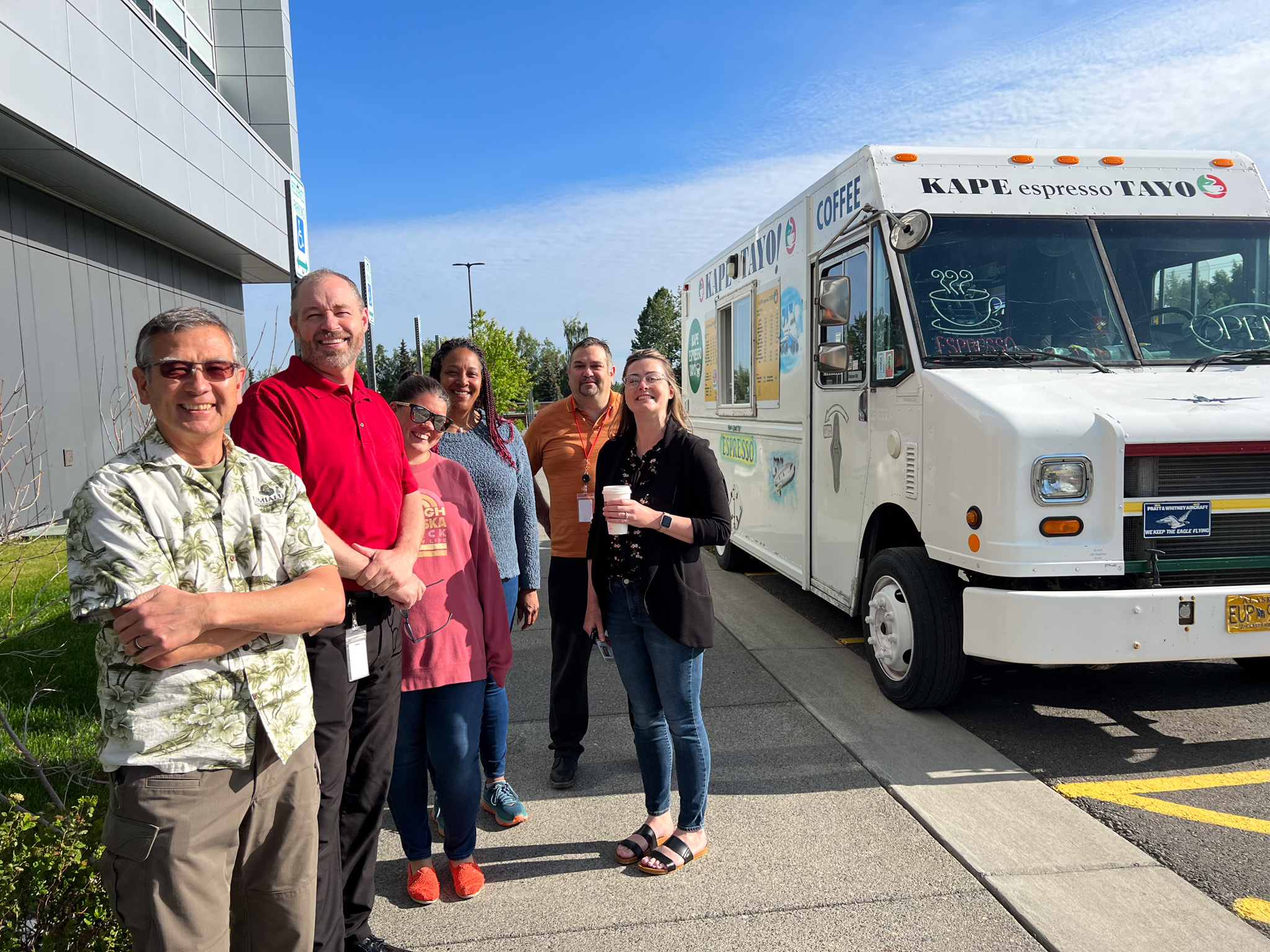 Group of Umialik employees standing together outdoors in front of a mobile coffee truck.