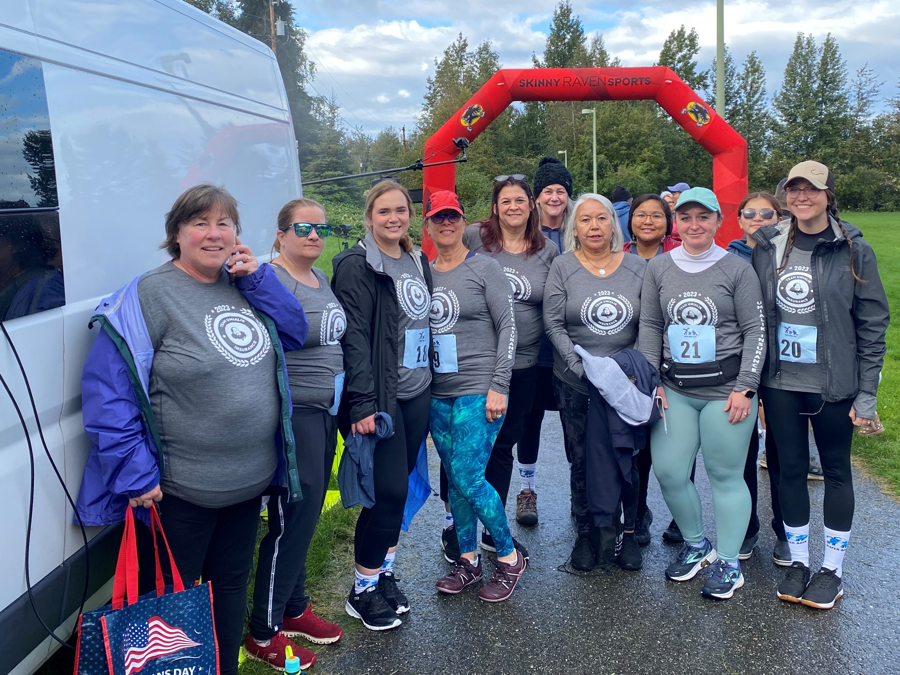Group of Umialik employees in athletic clothes and matching shirts standing together at the finish line of a race.
