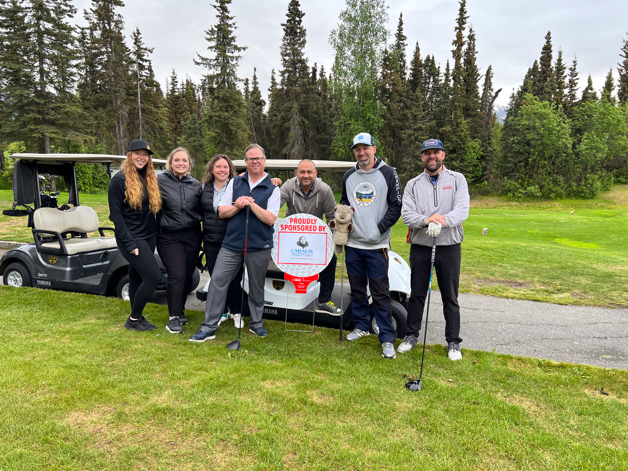 Group of Umialik employees gathered on a golf course.